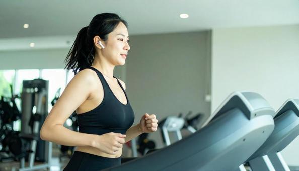ジムでランニングをする若い女性 ジムでランニングをする若い女性の写真