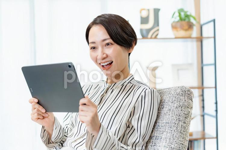 ソファに座りタブレットを見る女性 スマホ,ビジネス,メッセージの写真素材