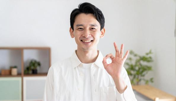 笑顔でOKサインをする白シャツの男性の写真