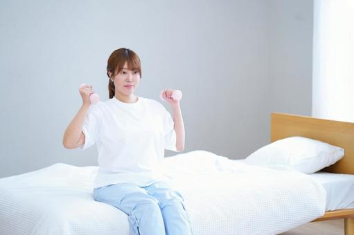 ベッドに座り両手にダンベルを持つ女性 女性,ダンベル,持つの写真素材
