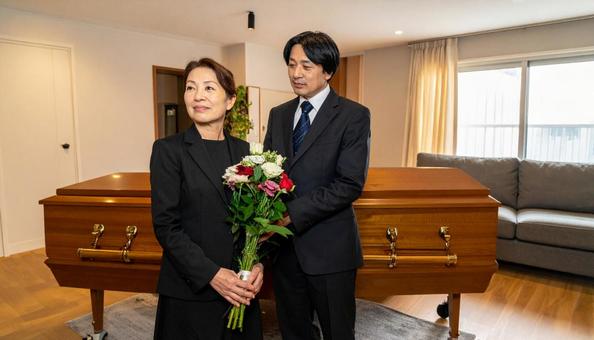 棺に花束を供えるミドルの男女の写真