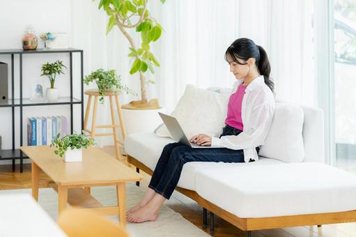 自宅でノートパソコンを操作する若い女性 若い女性,ノートパソコン,笑顔の写真素材