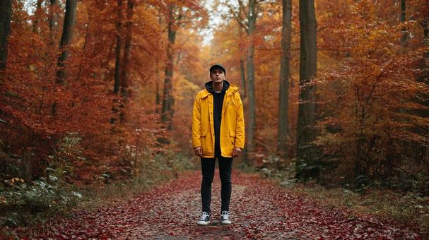 紅葉の中を歩く黄色い服の男性 紅葉の中を歩く黄色い服の男性の写真