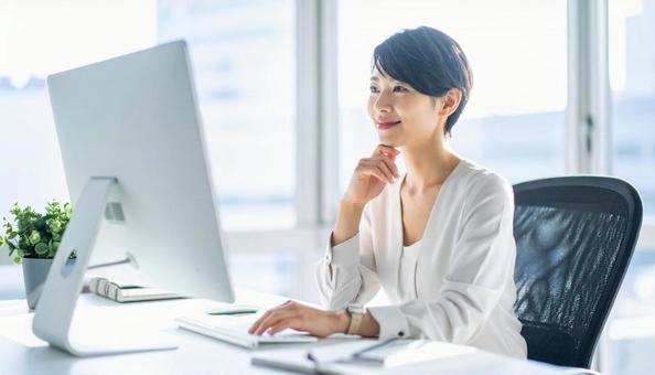 パソコンで仕事する白い服装の女性会社員 パソコンで仕事する白い服装の女性会社員の写真
