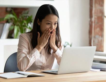 ノートPCを見て驚く女性 ノートPCを見て驚く女性の写真