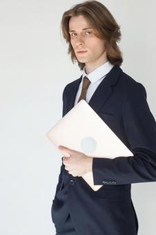 ノートパソコンを抱えているカメラ目線のスーツの男性 男性,外国人,欧米人の写真素材