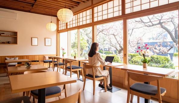 カフェでノートパソコンを開き仕事する女性 カフェでノートパソコンを開き仕事する女性の写真