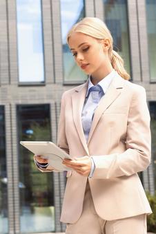 オフィスビルの外でタブレットを持って立っているビジネスウーマン ビジネスウーマン,ビジネス,女性の写真素材