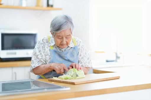 キャベツを切っているショートヘアの女性 女性,キャベツ,包丁の写真素材