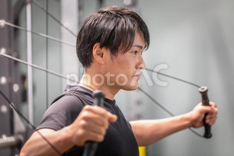 スポーツジムでケーブルマシンを使う男性 ケーブルマシン,ケーブル,ワークアウトの写真素材
