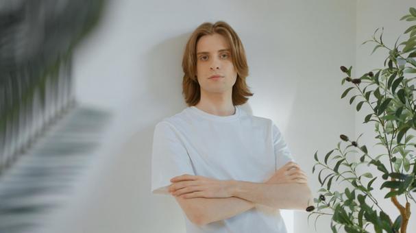 腕組みをして壁にもたれる白いTシャツを着たカメラ目線の男性 男性,外国人,欧米人の写真素材