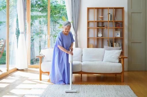 下を向き掃除機で掃除中の高齢女性 女性,掃除,掃除機の写真素材