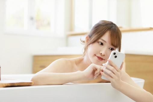 お風呂でスマートフォンを使う女性 お風呂でスマートフォンを使う女性 女性,人物,スマートフォンの写真素材
