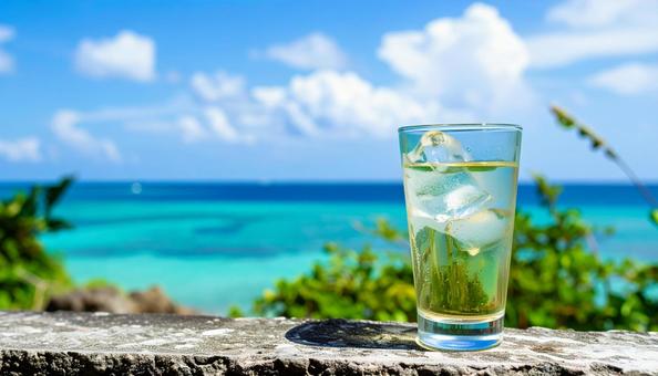 青い海を背景のグラスに注がれた泡盛の写真