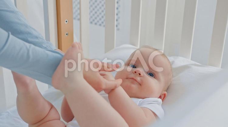 足で大人の手を挟もうとする笑顔の赤ちゃん 赤ちゃん,かわいい,笑うの写真素材