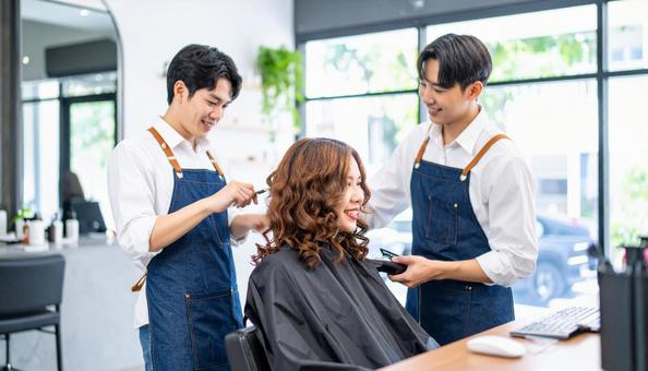 カットをする若い男性美容師の笑顔の横顔 カットをする若い男性美容師の笑顔の横顔の写真