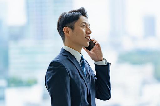 高層ビルで電話をするビジネスマン 高層ビルで電話をするビジネスマン ビジネスマン,男性,スーツの写真素材