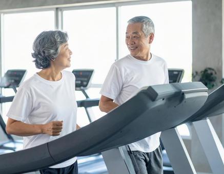 ランニングマシンで走る仲良しシニア夫婦 ランニングマシンで走る仲良しシニア夫婦の写真