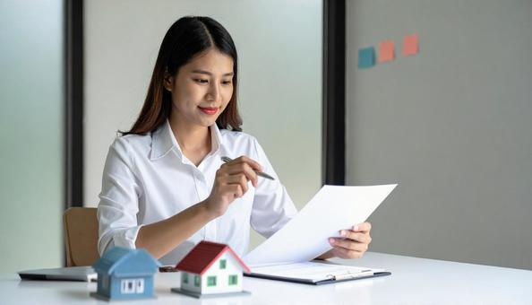 住宅ローンの書類と住宅模型を持つ女性 住宅ローンの書類と住宅模型を持つ女性の写真
