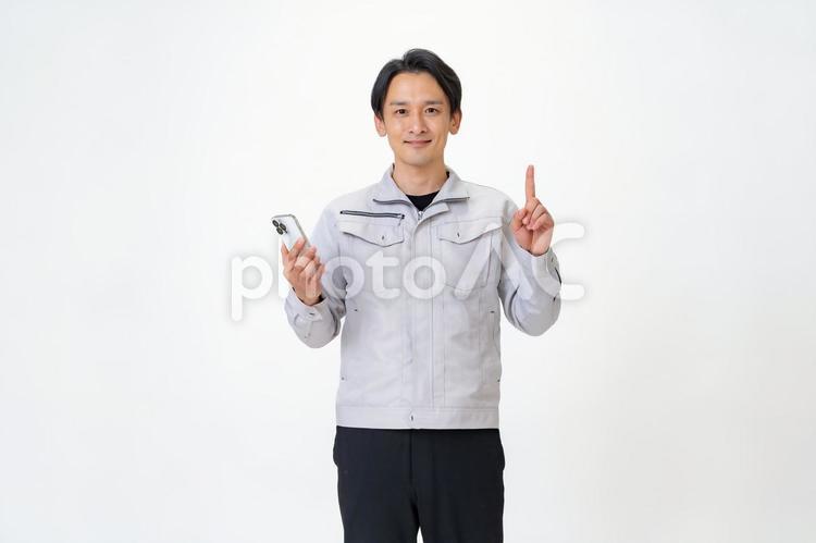 携帯を見る作業着を着た男性 日本人,点検,保守点検の写真素材