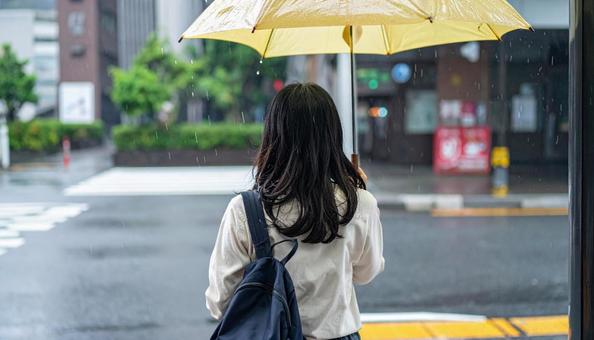 雨の中バス停でバスを待つ日本人女性 雨の中バス停でバスを待つ日本人女性の写真