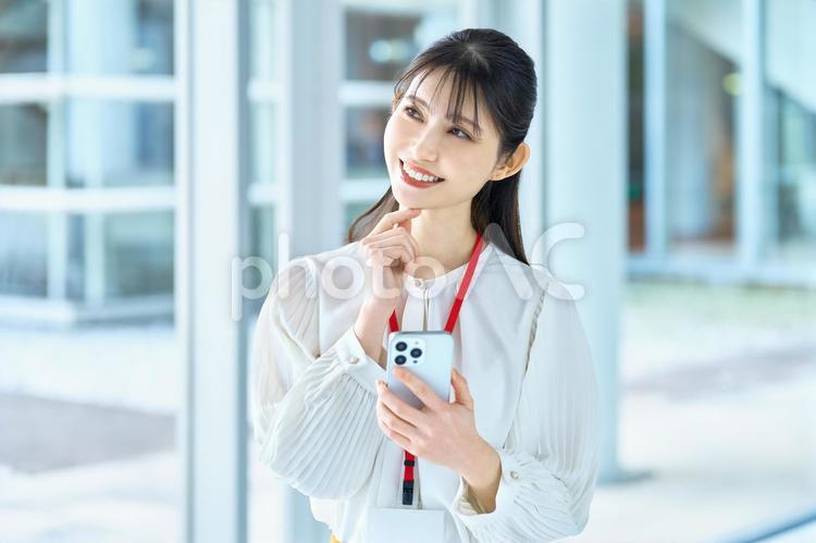 スマホ　女性　オフィス　考える　笑顔 スマホ,スマートフォン,女性の写真素材