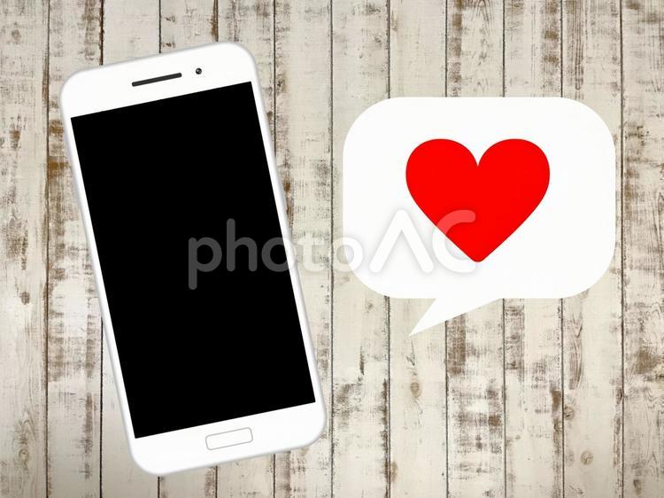 白い木目背景のスマートフォン(赤ハート) ハート,マッチング,アプリの写真素材