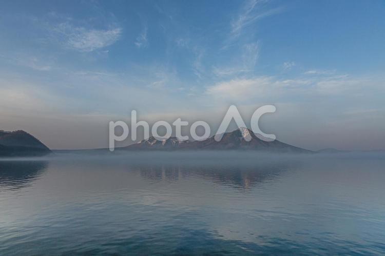 霞かかる朝の湖と山々 くも,ほっかいどう,みずうみの写真素材