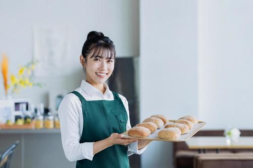 パンを持つカフェで働く若い女性 パンを持つカフェで働く若い女性の写真