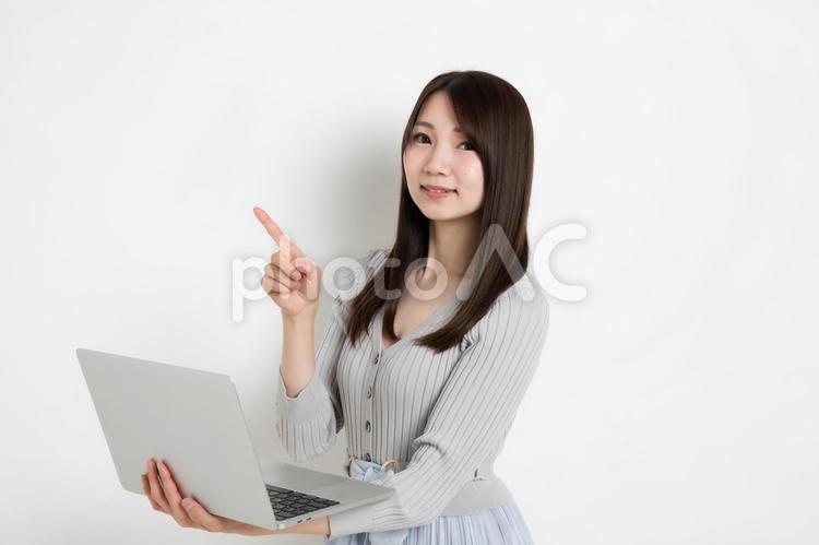 パソコンを持って指差ししている若い女性 女性,女の子,女の写真素材