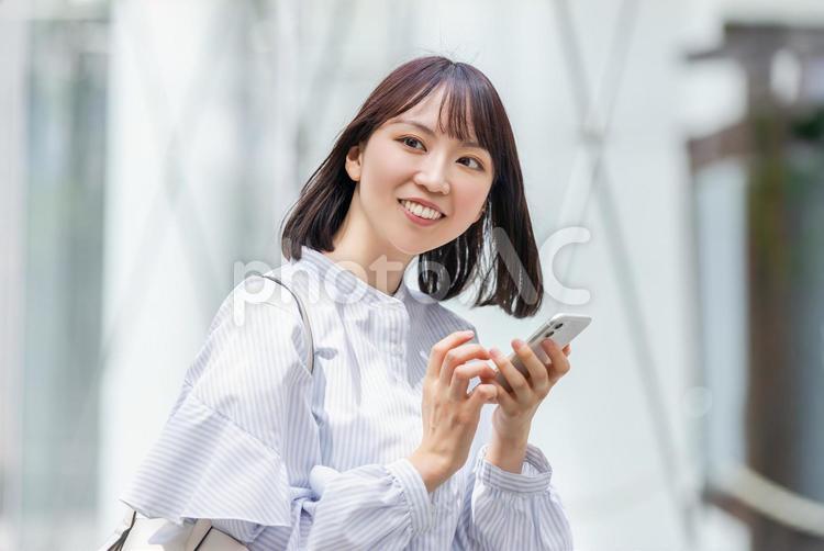 スマホを操作する笑顔のビジネスウーマン 女性,ビジネス,スマホの写真素材