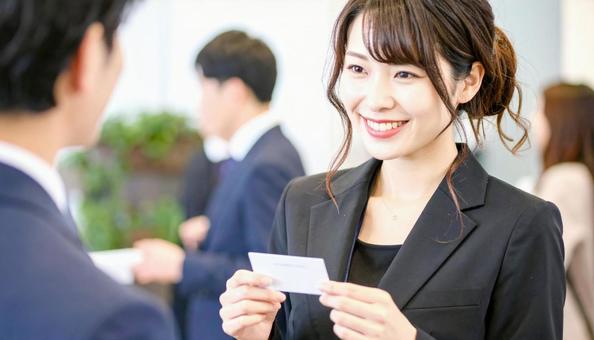 笑顔で名刺を持つ女性ビジネスパーソンの写真