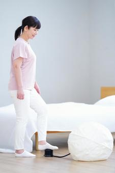 室内でバランスボールに空気を入れる中年女性の横向き姿 室内でバランスボールに空気を入れる中年女性の横向き姿 主婦,シニア,立ち姿の写真素材