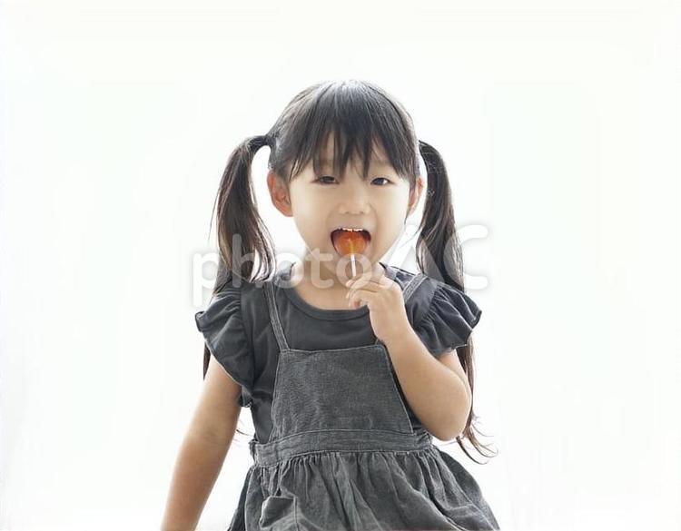 笑顔でペロペロキャンディを舐める子供 笑顔,子供,女の子の写真素材