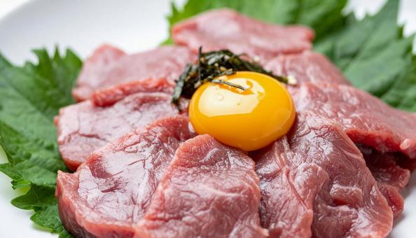 生卵の黄身がかかったユッケ 生卵の黄身がかかったユッケの写真