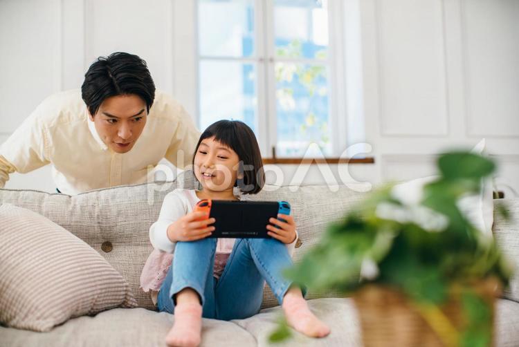後ろから娘に話し掛ける父 父子,ゲーム,親子の写真素材