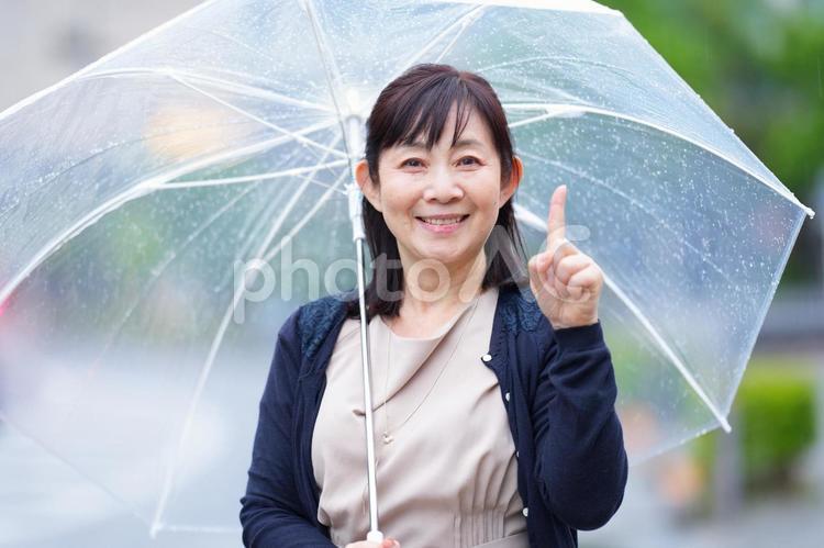 雨の中で指をさす笑顔の女性 主婦,シニア,中年の写真素材