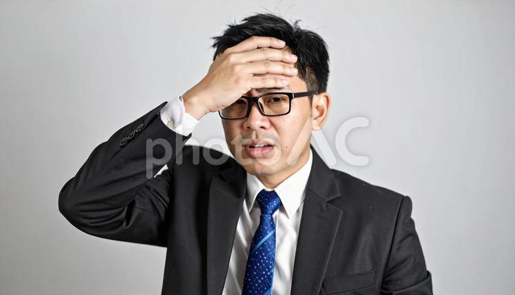 手を額に当てて苦悩するサラリーマン 苦悩,ストレス,心配の写真素材