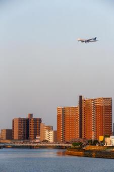 夕暮れの街と飛行機_縦 飛行機,夕暮れ,伊丹空港の写真素材