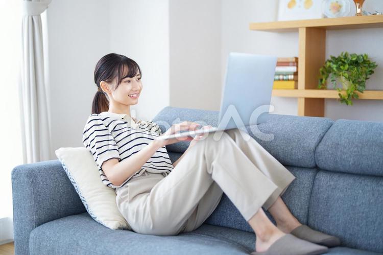 膝の上にパソコンをのせた笑顔の女性 女性,ノートパソコン,見るの写真素材
