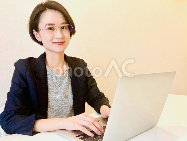笑顔でパソコン作業をするメガネの女性 在宅ワーク,女性,リモートワークの写真素材