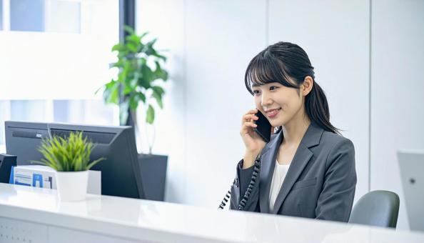 笑顔で対応する女性の受付嬢 笑顔で対応する女性の受付嬢の写真
