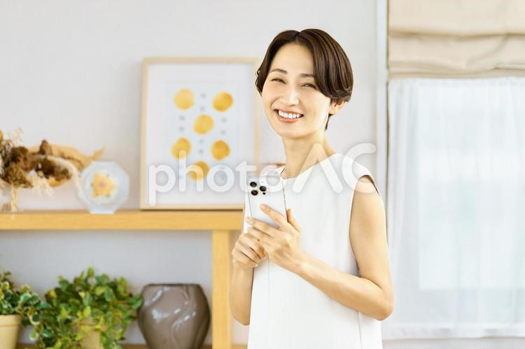 スマホを持つ女性　リビング　主婦 スマホ,女性,主婦の写真素材