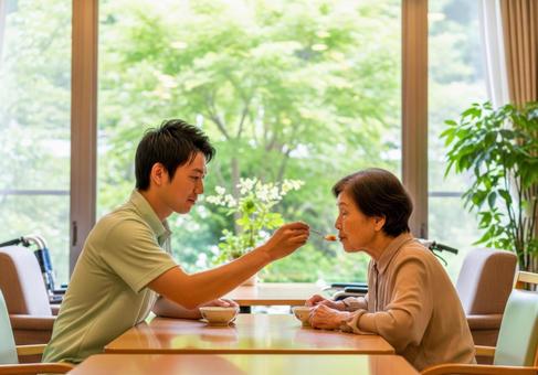男性介護士が高齢女性に食事介助する場面 男性介護士が高齢女性に食事介助する場面の写真
