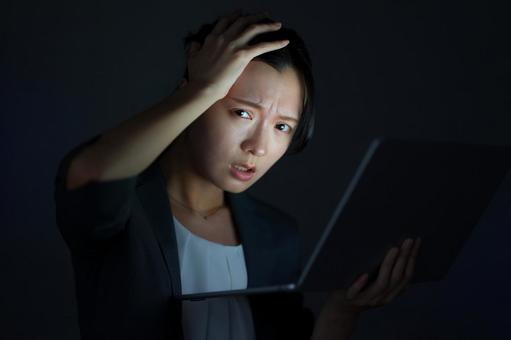 女性がノートPCを見て髪を触りながら悩む 女性,頭を抱える,悩むの写真素材