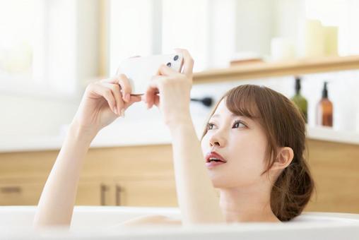 お風呂でスマートフォンを使う女性 お風呂でスマートフォンを使う女性 女性,人物,スマートフォンの写真素材