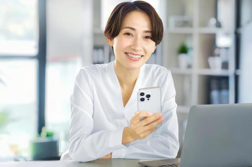 スマホを使うビジネスウーマン パソコン スマホを使うビジネスウーマン パソコン ビジネスウーマン,ノートパソコン,スマホの写真素材