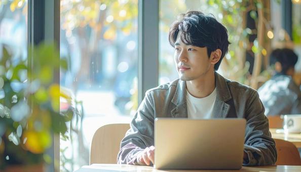 カフェでノートパソコンを使う日本人男性の写真