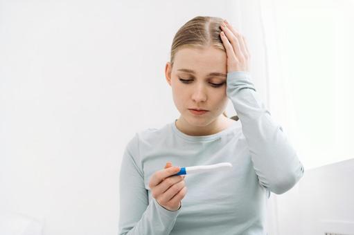 妊娠検査薬を見て頭に手を当てる女性 妊娠検査薬を見て頭に手を当てる女性 女性,妊娠検査薬,持つの写真素材