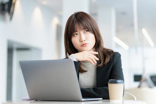 パソコンを使いながら考えごとをする女性 パソコンを使いながら考えごとをする女性 女性,パソコン,考えるの写真素材